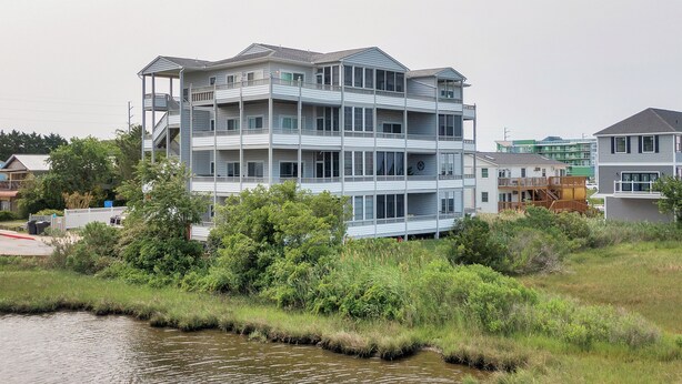 A multi-story building with balconies, located near a body of water. - New For 2025! Two Bedroom Bayfront Condo On 79th St (Ocean City)