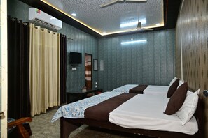 Une chambre d’hôtel avec deux lits, un ventilateur de plafond, un appareil de climatisation et un téléviseur.