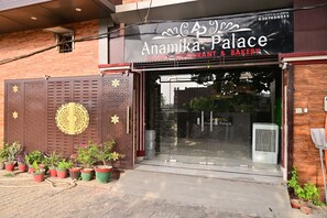 Un restaurant et une boulangerie à la façade moderne, avec une entrée en verre et des plantes en pot décoratives à l’extérieur.