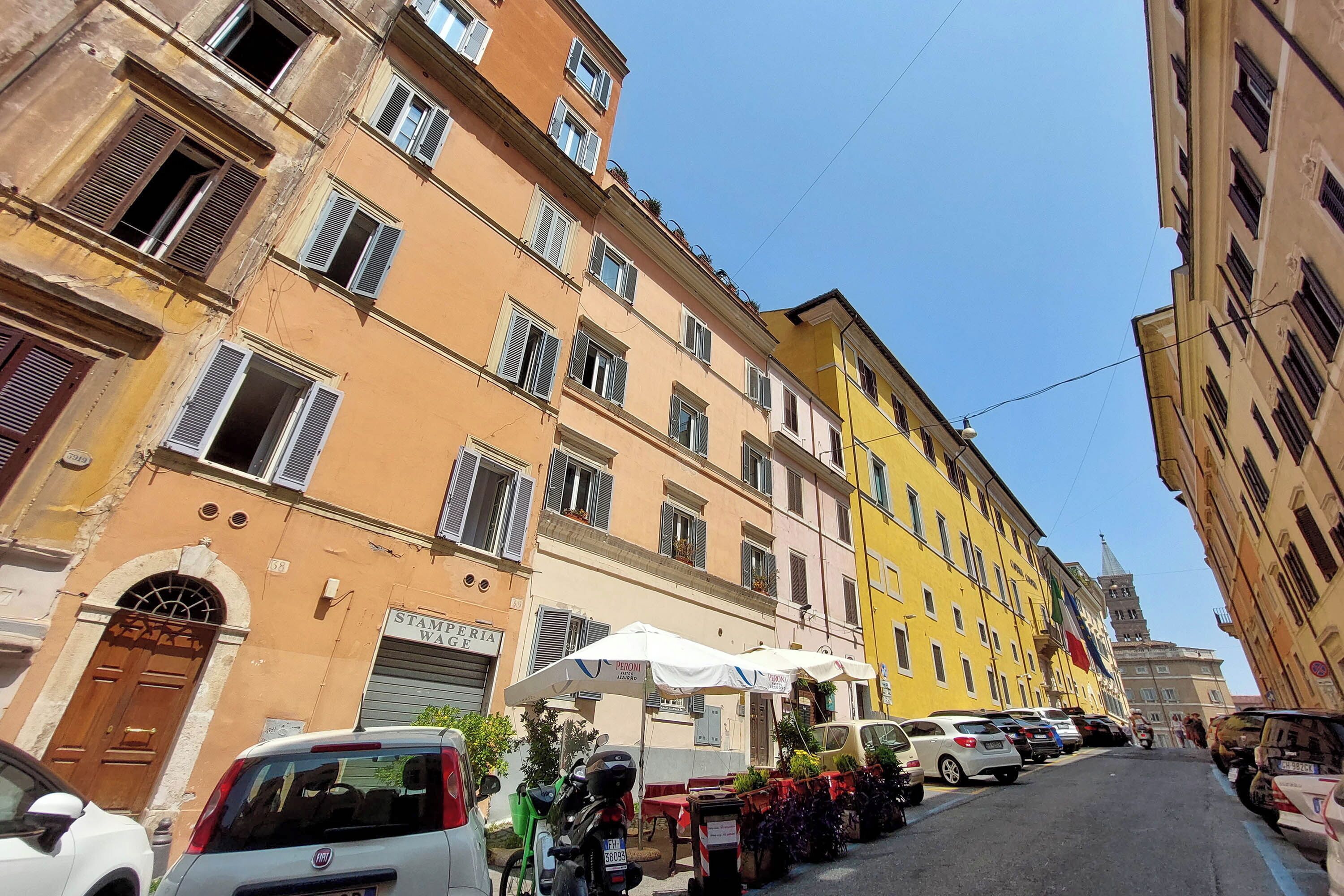A street with parked cars and a row of colorful buildings.