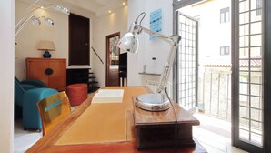 A room with a desk, a lamp, a chair, a sofa, and a window with a view of buildings. - Secret refuge in the heart of Rome (Roma)