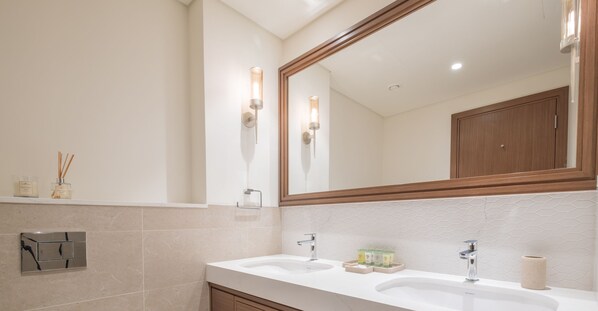 Ein modernes Badezimmer mit zwei Waschbecken, einem großen Spiegel und einem Handtuchspender.