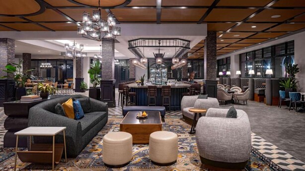 A spacious lobby with a bar area, seating arrangements, and a chandelier. - Near Bourbon Street | Pool, Dining & Pet-friendly (New Orleans)
