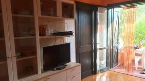 Een kamer met een kast met servies en een flatscreen televisie.