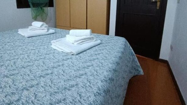 Een slaapkamer met een bed, een kledingkast, een deur en een raam met gordijn.