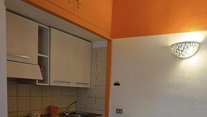 Een kleine keuken met witte kastjes, een tafeltje en een broodrooster.