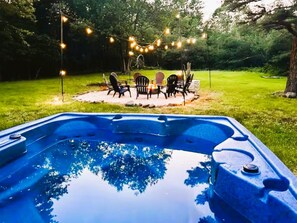 A hot tub with a patio area, surrounded by trees and string lights. - Pocono Vacation Home + Steps to Lake + Minutes to Kalahari & Camelback + Firepit (Long Pond)
