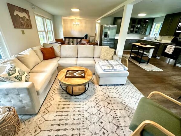 Un salon moderne avec un canapé d’angle, une table basse et un tapis à motifs.