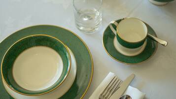A table set with green and white plates, bowls, a teapot, and silverware.