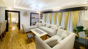 A modern living room with a sofa set, a coffee table, and a dining table. There is a bookshelf with decorative items and a mirror on the wall. - BRIKitt Himaliyan Vista 2BHK - Mukteshwar, Nainital (Mukteshwar)