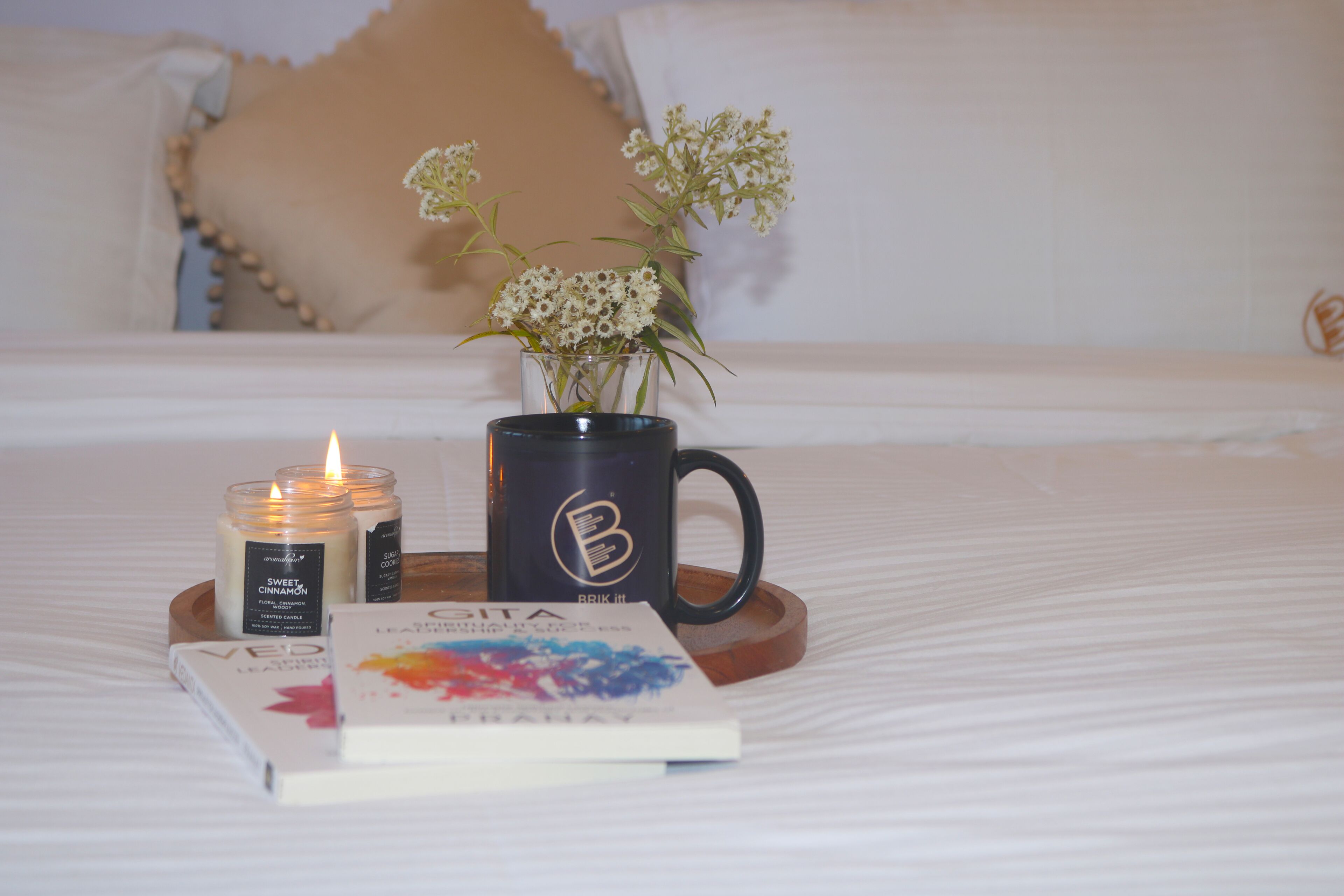 Ein Bett mit Tablett, darauf ein Buch, eine Kerze und eine Tasse.