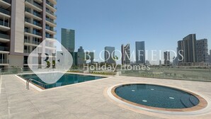 A rooftop pool area with a city skyline in the background.
