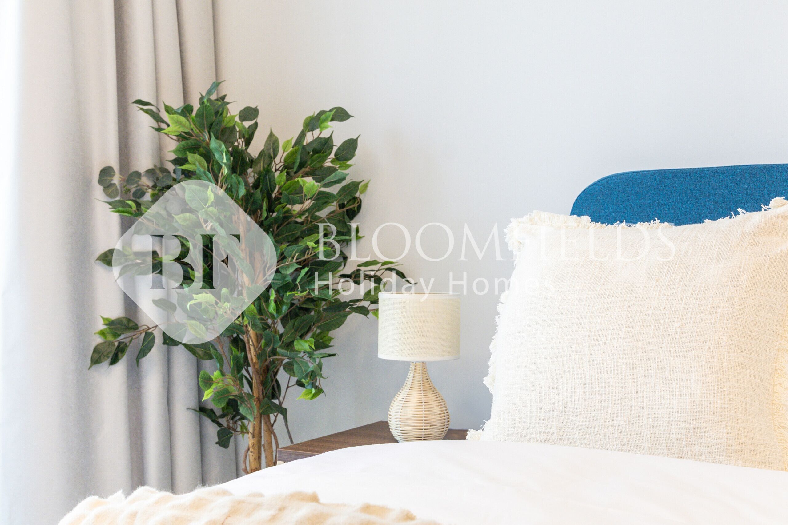 Une chambre à coucher bien rangée, avec un lit, une lampe de chevet et une plante en pot.