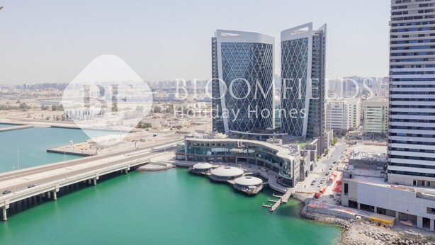 A modern hotel with a waterfront view, featuring a distinctive architectural design with two prominent towers and a curved building.