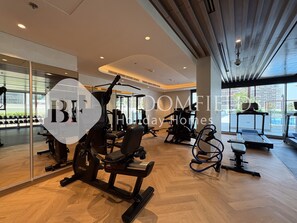 Een ruime sportschool met diverse fitnessapparaten, grote ramen en een modern design.