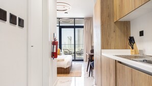 Eine moderne Küche mit Holzausbau, einer weißen Arbeitsplatte und Blick auf einen Balkon mit Sitzgelegenheit.