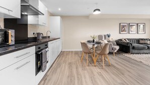 Uma cozinha moderna com armários brancos, forno embutido e área de jantar com mesa e cadeiras.