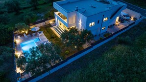Una casa moderna de dos pisos con piscina, mobiliario exterior y garaje.