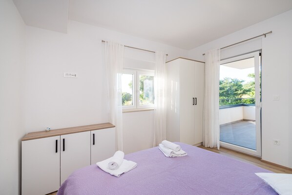 A bedroom with a bed, a wardrobe, a window, and a balcony. - Apartment Vista Mare 1 with heated pool (Sveti Filip i Jakov)