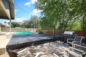 Un jardin avec une piscine, un barbecue et un espace salon extérieur.