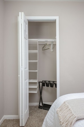 Une chambre à coucher avec un placard comprenant un espace pour suspendre des vêtements et des étagères.