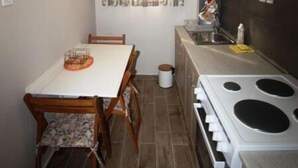 Cocina compacta con una mesa, sillas, estufa y una ventana con cortinas.