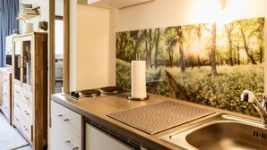 A modern kitchen with a wooden countertop, a stainless steel sink, and a wall-mounted shelf with books and decorative items.