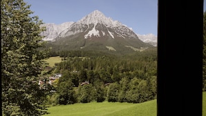 Een berglandschap met uitzicht op een huis en omliggend bos.