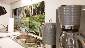 Een keuken met een koffiezetapparaat, een waterkoker en een fornuis.