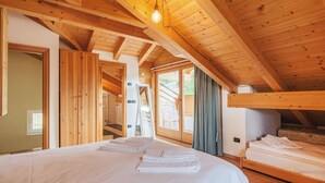 A wooden cabin with a large bed, a small sofa, and a window with curtains.