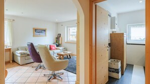 A living room with a sofa, two chairs, a small table, a bookshelf, and a window.