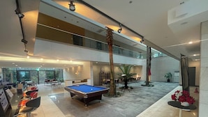 Un grand espace intérieur comprenant une table de billard, des sièges et un palmier.