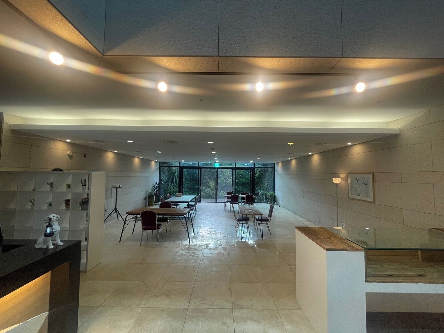Un hall d’hôtel spacieux et moderne, doté d’un espace salon central, d’un comptoir d’accueil et d’une paroi en verre donnant sur l’extérieur.