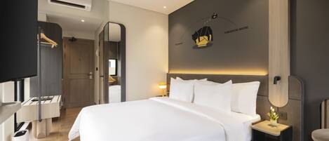 A modern hotel room with a large bed, bedside tables, a mirror, and a wall-mounted artwork.
