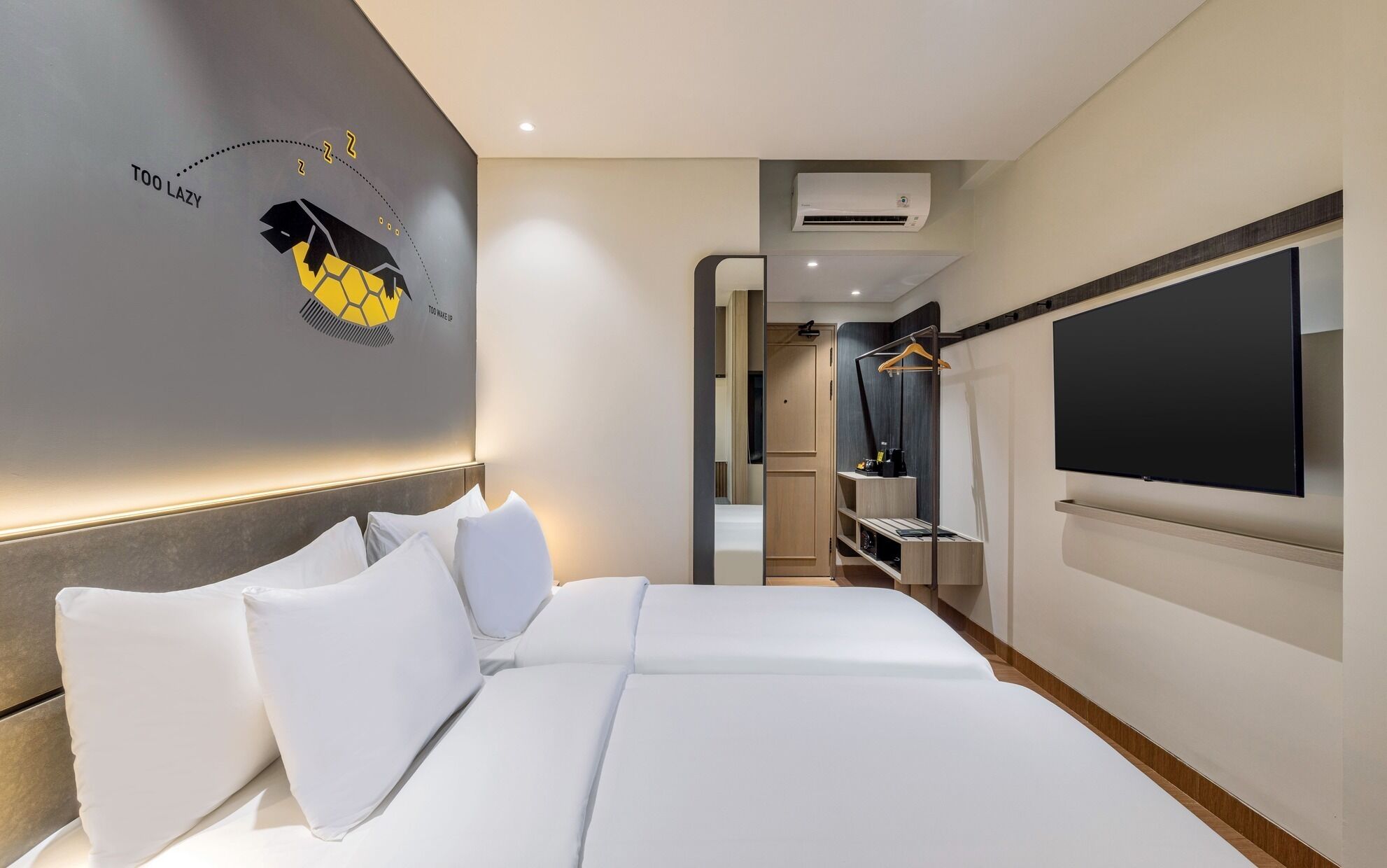 A modern hotel room with a large bed, a TV mounted on the wall, and a wardrobe with a mirror.