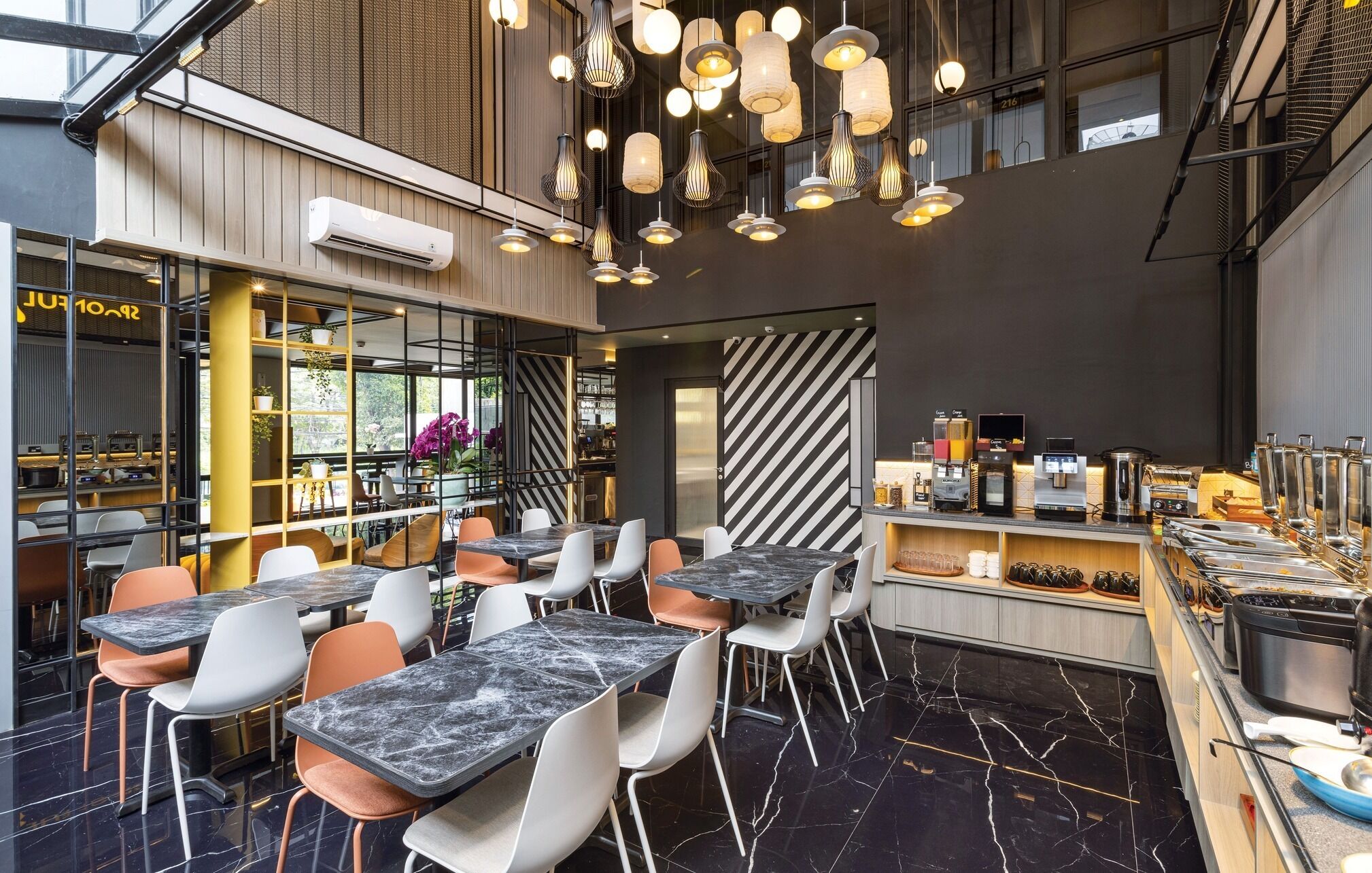 A modern cafe with marble tables and chairs, hanging pendant lights, and a coffee bar with various brewing equipment.
