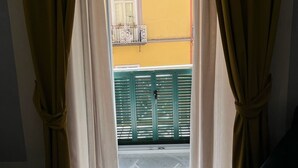 Ein Zimmer mit Fenster, Vorhängen und Blick auf einen Balkon.