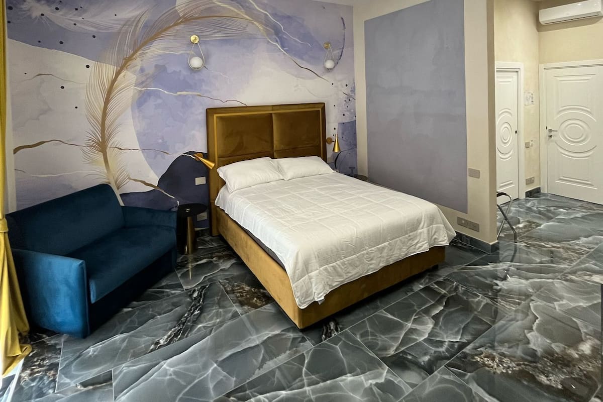 A modern bedroom with a bed, a blue armchair, and a marble floor.