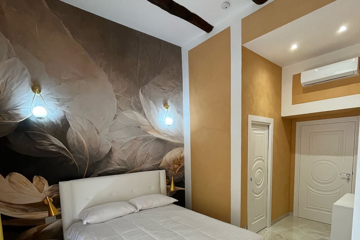 A modern bedroom with a large bed, a wall mural, and a built-in wardrobe.