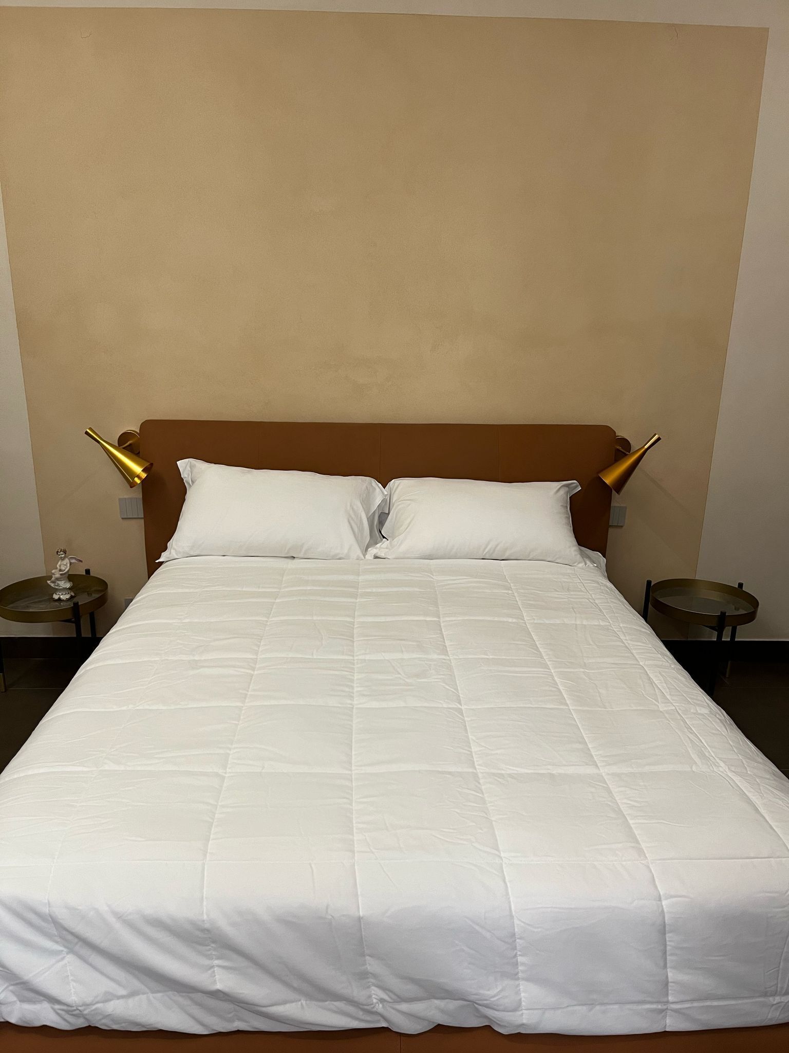 A neatly made bed with a white duvet, a wooden headboard, and two bedside tables with lamps.