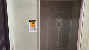 Ein Flur mit einer Tür mit der Aufschrift 'RELAIS CHIAIA' und einem Schild für eine Überwachungskamera an der Wand.