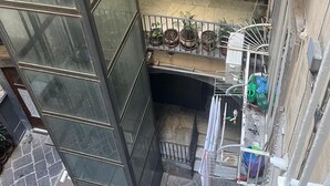 Ein mehrstöckiges Wohngebäude mit einem Balkon im oberen Bereich, einer Treppe und Pflanzen in Töpfen im unteren Bereich.