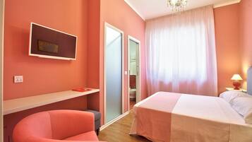 Ein Schlafzimmer mit Bett, Stuhl, Schreibtisch, Spiegel und einer Chandelüster.