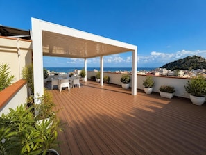 A wooden deck with outdoor furniture, a white pergola, and potted plants. - B&B del Corso (Capo d'Orlando)