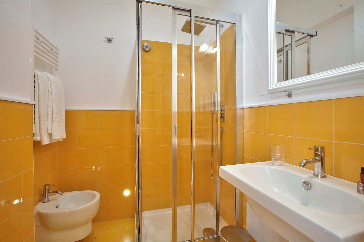A bathroom with a glass-enclosed shower, a sink, and a bidet.