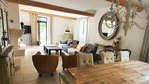 A spacious living room with a wooden dining table, sofas, and a chandelier. - Rare product: Top-of-the-range Provencal farmhouse in the heart of the vineyards (Villedieu)