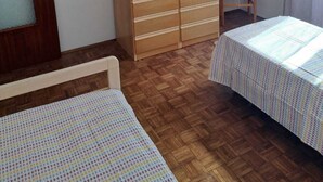 A room with two beds, a wardrobe, a chair, and a door. - RED FOUNTAIN HOUSE 2 (arizzano)