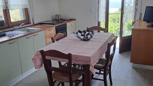 A compact kitchen with a dining area, a built-in oven, and a view through the glass door. - RED FOUNTAIN HOUSE 2 (arizzano)