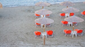A beach with rows of orange chairs and thatched umbrellas. - Aggelika Apartments (Zakynthos)