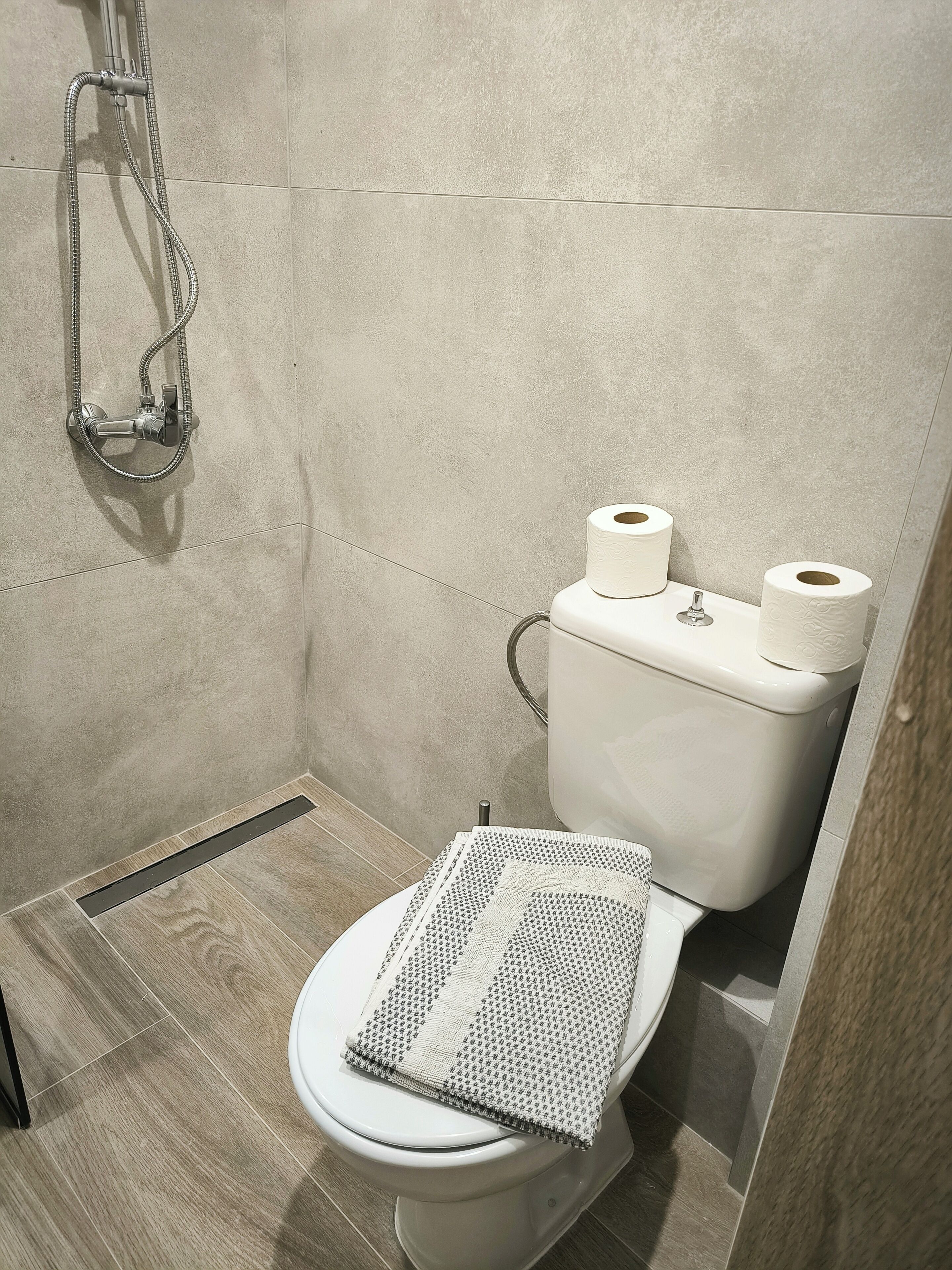 A modern bathroom with a shower, toilet, and a mat on the floor.